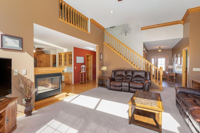 living room featuring a towering ceiling, light hardwood / wood-style floors, ceiling fan, crown molding, and a multi sided fireplace