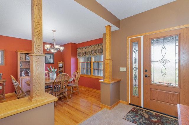 entryway with light hardwood / wood-style floors, a chandelier, and ornate columns