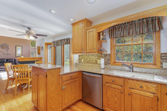 kitchen with stainless steel dishwasher, kitchen peninsula, light wood-type flooring, and plenty of natural light