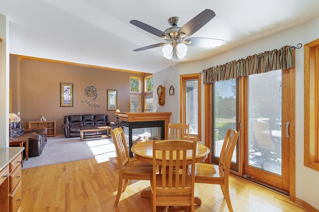 dining room featuring light hardwood / wood-style floors, a multi sided fireplace, and ceiling fan