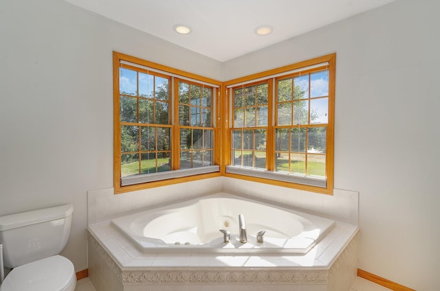 bathroom featuring tiled tub and toilet