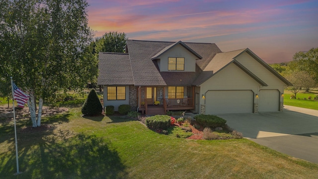 view of front of house with a yard, a porch, and a garage