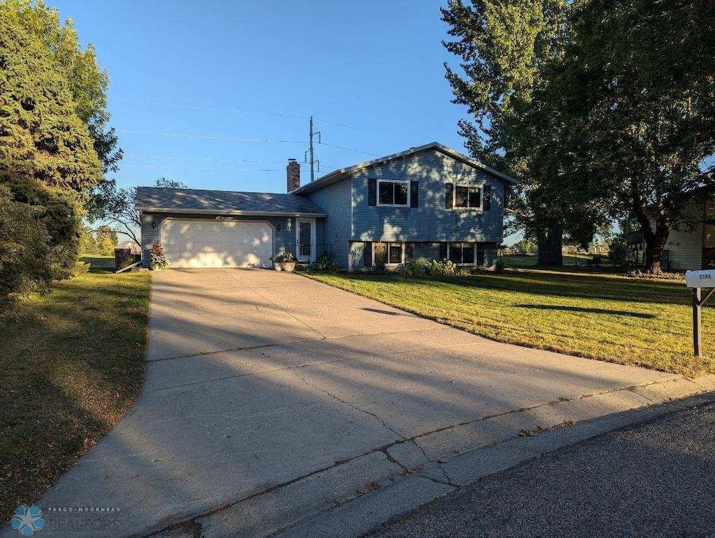 split level home featuring a garage and a front lawn