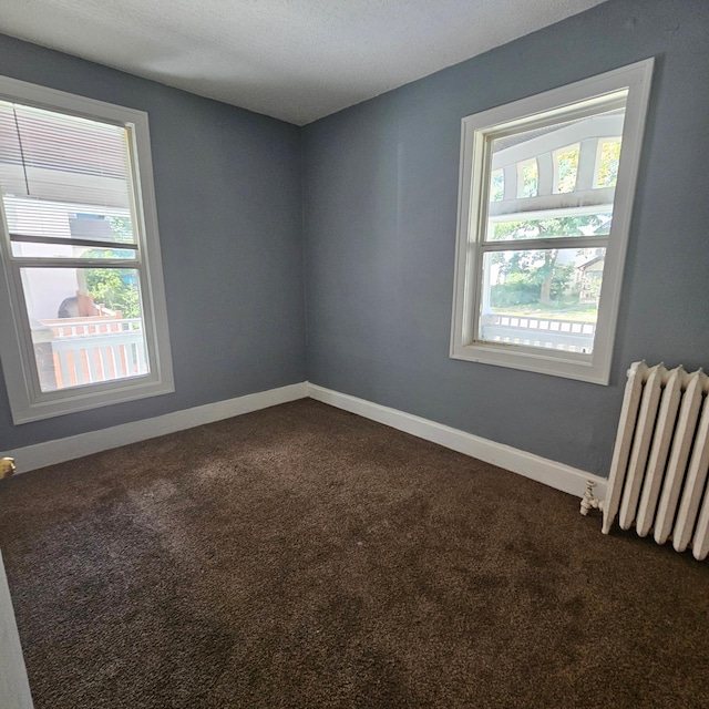 carpeted empty room with a textured ceiling and radiator heating unit