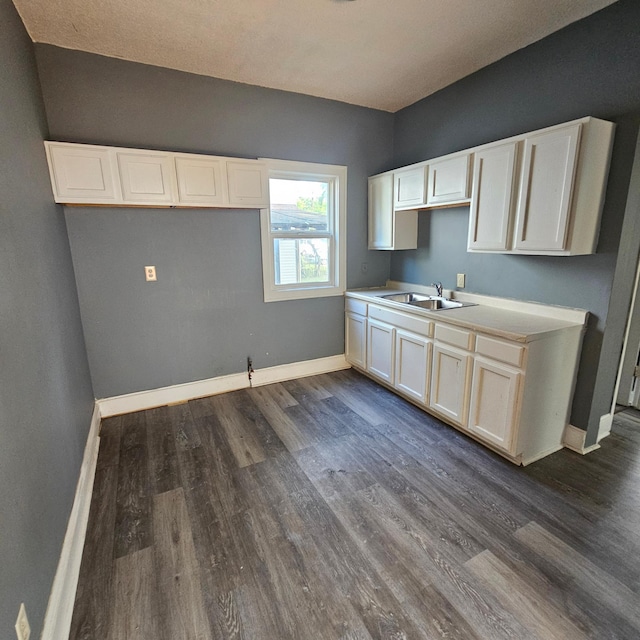 kitchen featuring dark wood-type flooring, sink, and white cabinetry