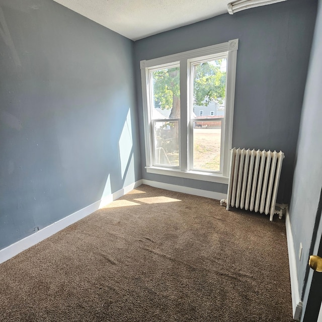 carpeted empty room featuring a textured ceiling and radiator heating unit