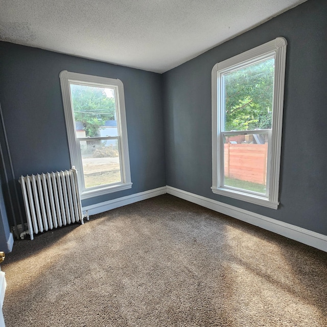 unfurnished room featuring a textured ceiling, a healthy amount of sunlight, carpet, and radiator heating unit