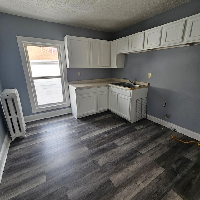 kitchen featuring a textured ceiling, dark hardwood / wood-style floors, sink, white cabinets, and radiator heating unit