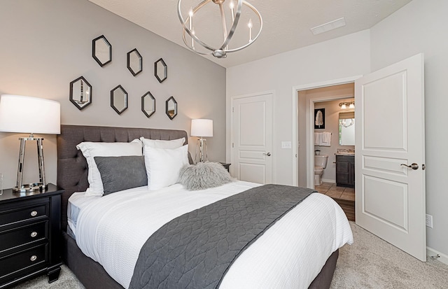 carpeted bedroom with a textured ceiling, an inviting chandelier, and ensuite bath