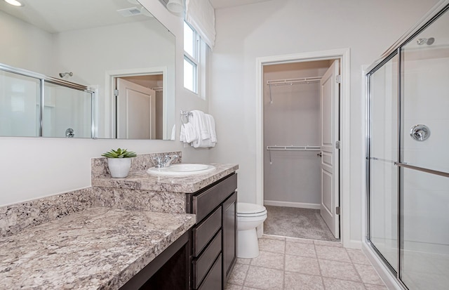 bathroom featuring tile patterned flooring, vanity, toilet, and an enclosed shower