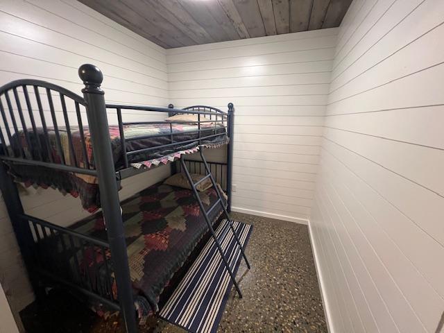 42911 County Highway 53, Pine Lake Twp, MN 56567 - bedroom featuring wood walls, wood ceiling, speckled floor, and baseboards