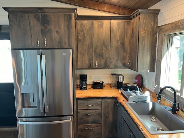 42911 County Highway 53, Pine Lake Twp, MN 56567 - kitchen with stainless steel fridge with ice dispenser, a sink, dark brown cabinets, light countertops, and wooden walls