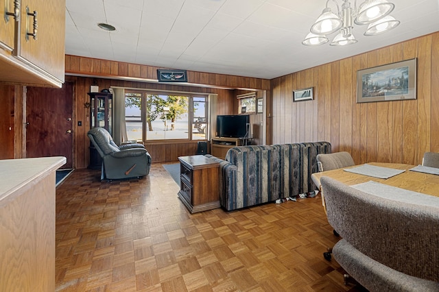 living room featuring wood walls, parquet floors, and a chandelier