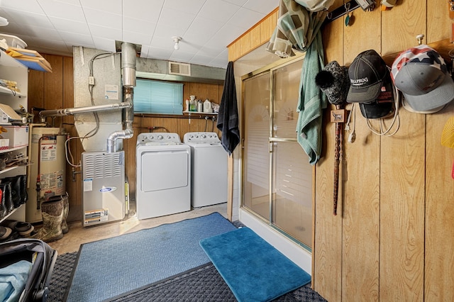 clothes washing area with separate washer and dryer, wooden walls, and water heater