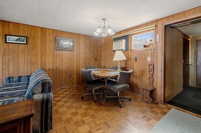 dining space with an AC wall unit, parquet floors, wooden walls, and an inviting chandelier