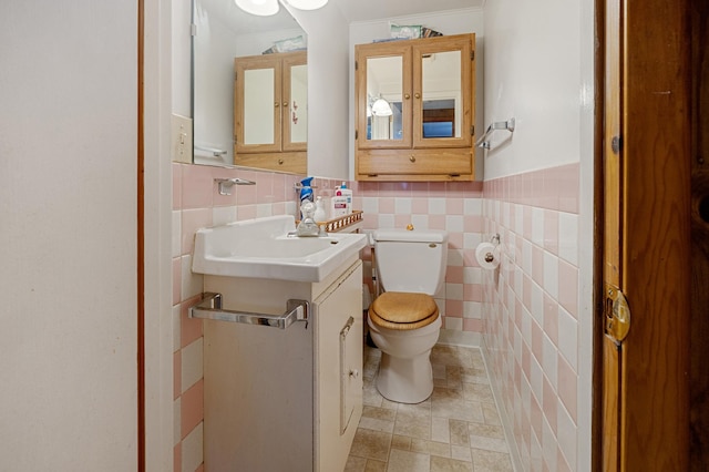 bathroom with vanity, toilet, and tile walls