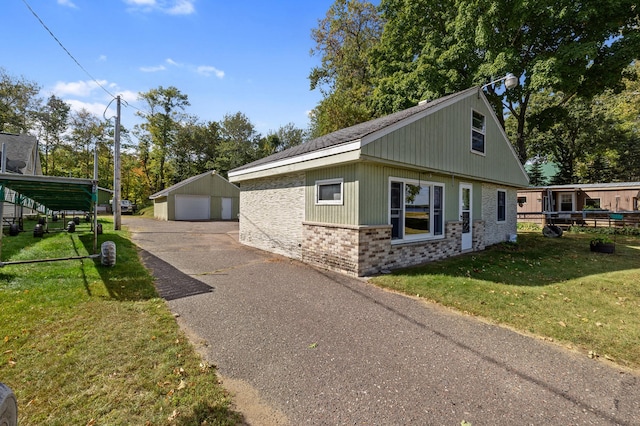 view of property exterior featuring a lawn, a garage, and an outdoor structure