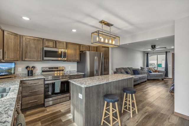 kitchen featuring pendant lighting, dark wood-type flooring, a breakfast bar, appliances with stainless steel finishes, and a kitchen island