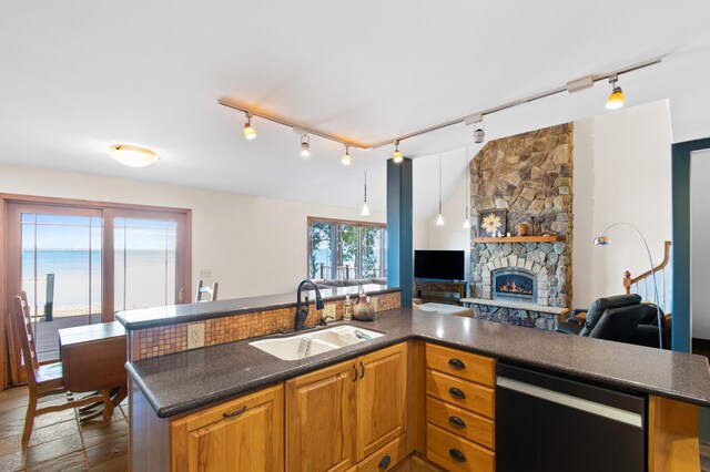 kitchen featuring dishwashing machine, a fireplace, track lighting, decorative light fixtures, and sink