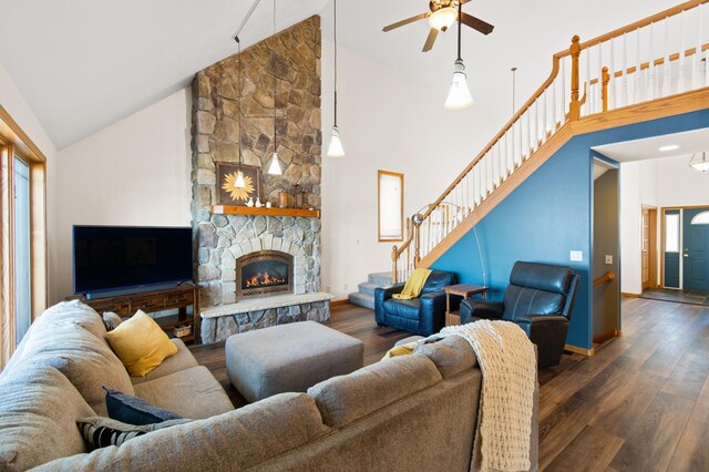 living room with ceiling fan, a stone fireplace, dark hardwood / wood-style flooring, and high vaulted ceiling