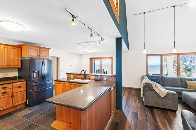 kitchen with decorative light fixtures, dark wood-type flooring, stainless steel fridge, and sink