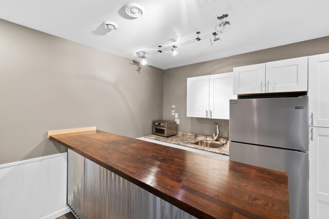 kitchen with white cabinetry, wood counters, high end refrigerator, and sink