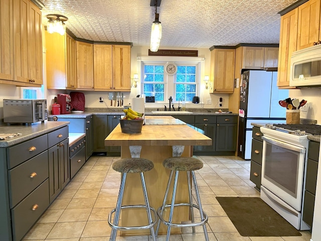 kitchen featuring sink, white appliances, wooden counters, gray cabinetry, and a center island