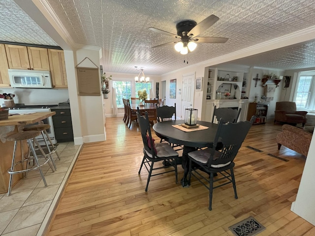 dining area featuring ceiling fan with notable chandelier, ornamental molding, and light hardwood / wood-style floors