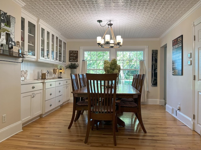 dining space with ornamental molding, a chandelier, and light hardwood / wood-style floors