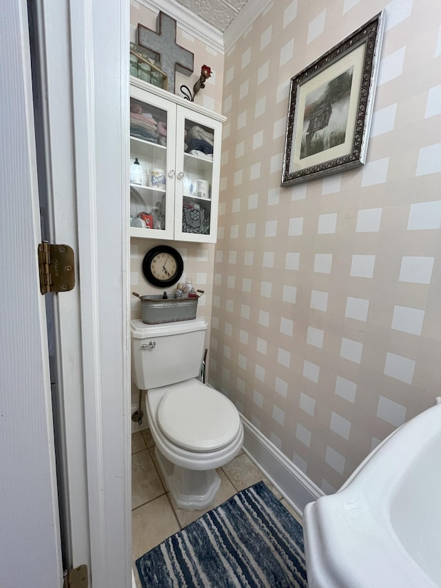 bathroom featuring tile patterned flooring, crown molding, and toilet