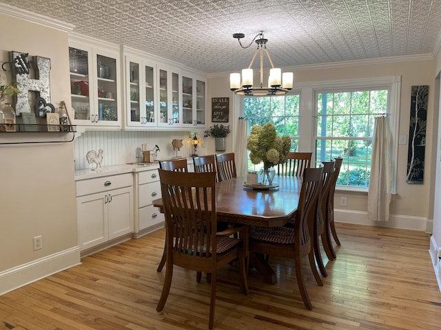 dining room with a notable chandelier, ornamental molding, and light wood-type flooring