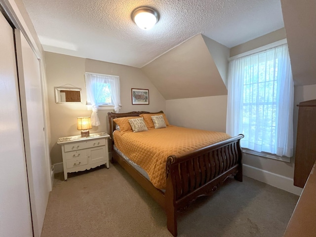 bedroom with lofted ceiling, light colored carpet, a textured ceiling, and a closet