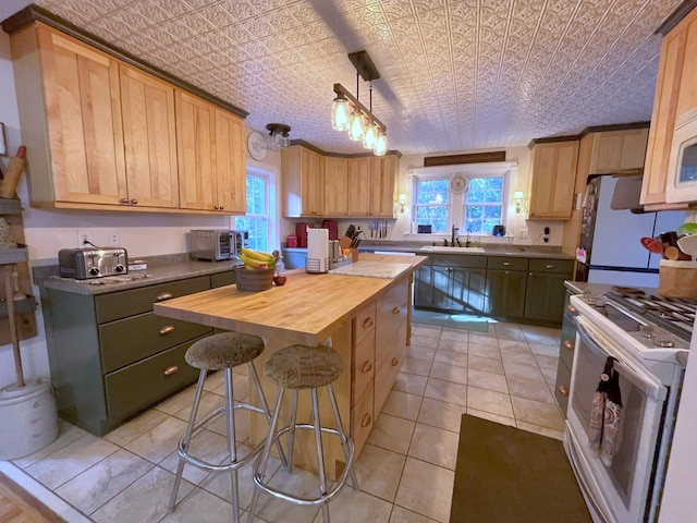 kitchen with pendant lighting, sink, wooden counters, a center island, and gas range gas stove