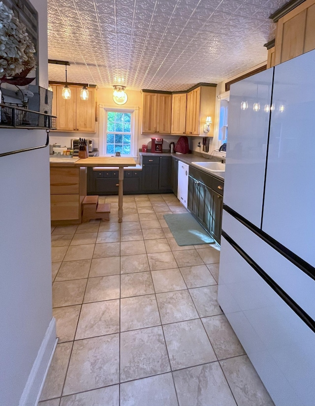 kitchen with light tile patterned flooring, sink, white dishwasher, and decorative light fixtures