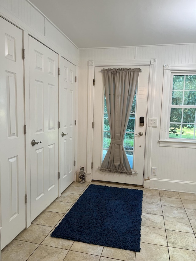 doorway featuring light tile patterned floors and wooden walls