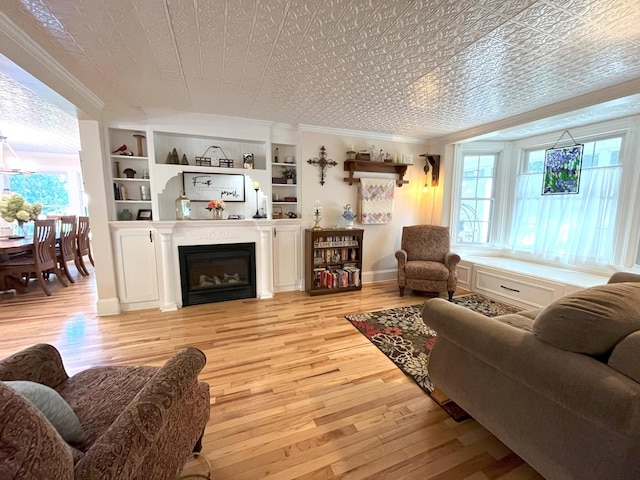 living room featuring crown molding, built in features, and light hardwood / wood-style flooring