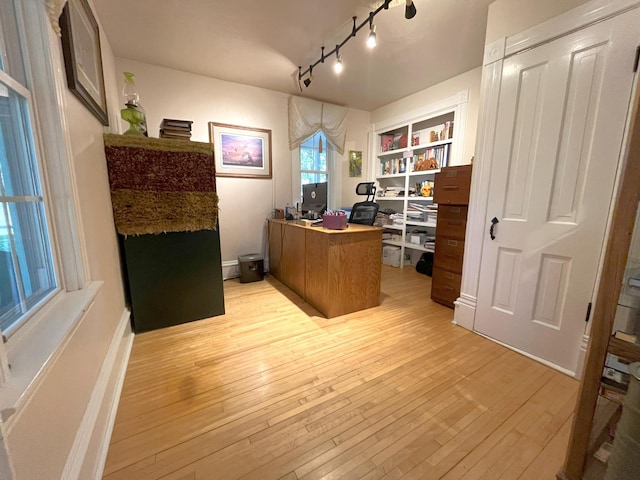 home office featuring built in shelves and light hardwood / wood-style flooring