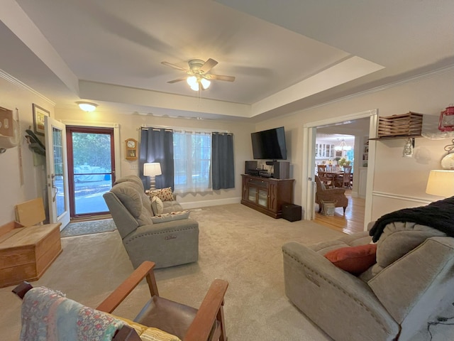 carpeted living room featuring ornamental molding, ceiling fan, and a tray ceiling