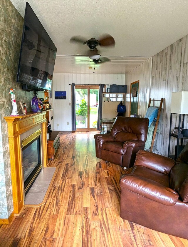 506 Ash Ave N, New Richland, MN 56072 - living room with a fireplace with flush hearth, a textured ceiling, wood finished floors, wood walls, and ceiling fan