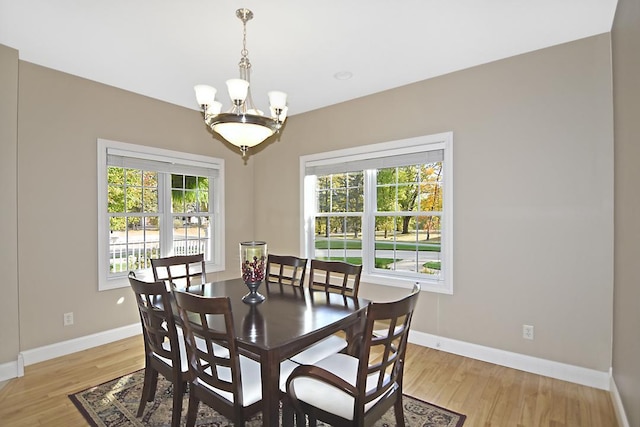 dining room featuring light wood-style floors, baseboards, a wealth of natural light, and a chandelier