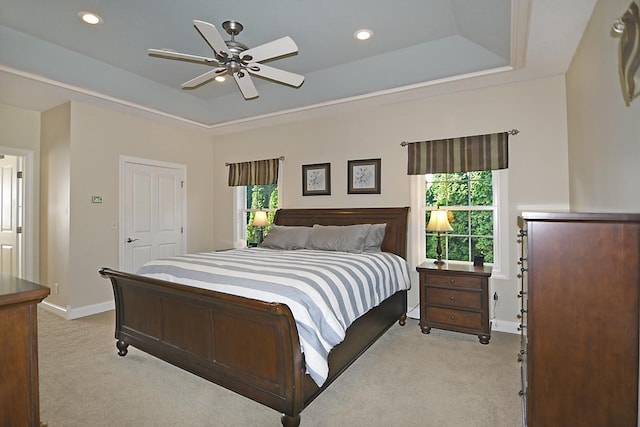 bedroom featuring a tray ceiling, multiple windows, and light colored carpet