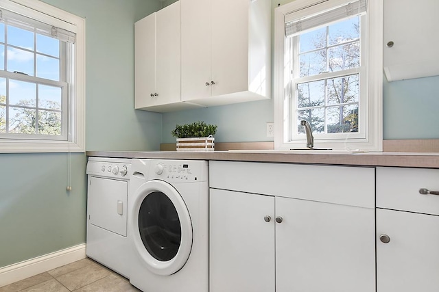 laundry area featuring light tile patterned floors, baseboards, cabinet space, a sink, and independent washer and dryer