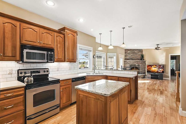 2002 Hazel Hill Rd SE, Alexandria, MN 56308 - kitchen featuring stainless steel appliances, a peninsula, tasteful backsplash, a ceiling fan, and a stone fireplace