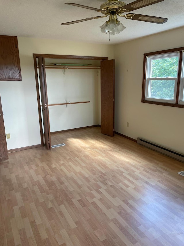 unfurnished bedroom with ceiling fan, a textured ceiling, light wood-type flooring, and a baseboard heating unit