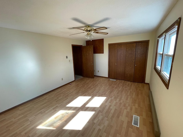 unfurnished bedroom with light wood-type flooring, ceiling fan, and a closet