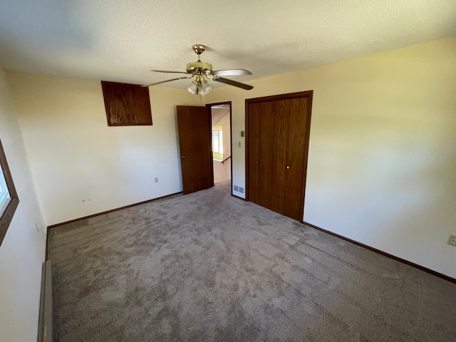 carpeted empty room with ceiling fan, a textured ceiling, and a baseboard heating unit