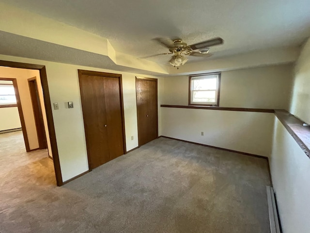 unfurnished bedroom featuring ceiling fan, two closets, and light carpet