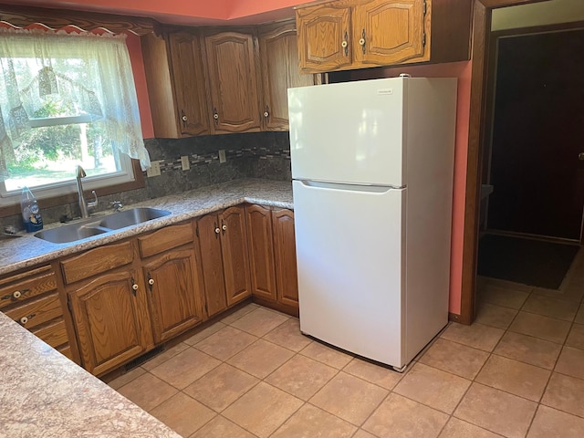 kitchen with decorative backsplash, white refrigerator, light tile patterned floors, and sink