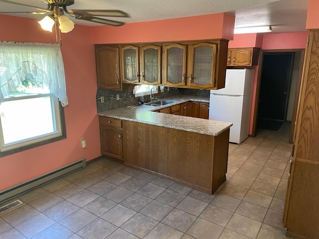 kitchen featuring decorative backsplash, white refrigerator, kitchen peninsula, ceiling fan, and sink