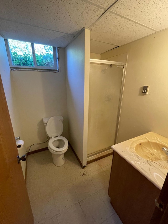 bathroom with a drop ceiling, vanity, toilet, and an enclosed shower